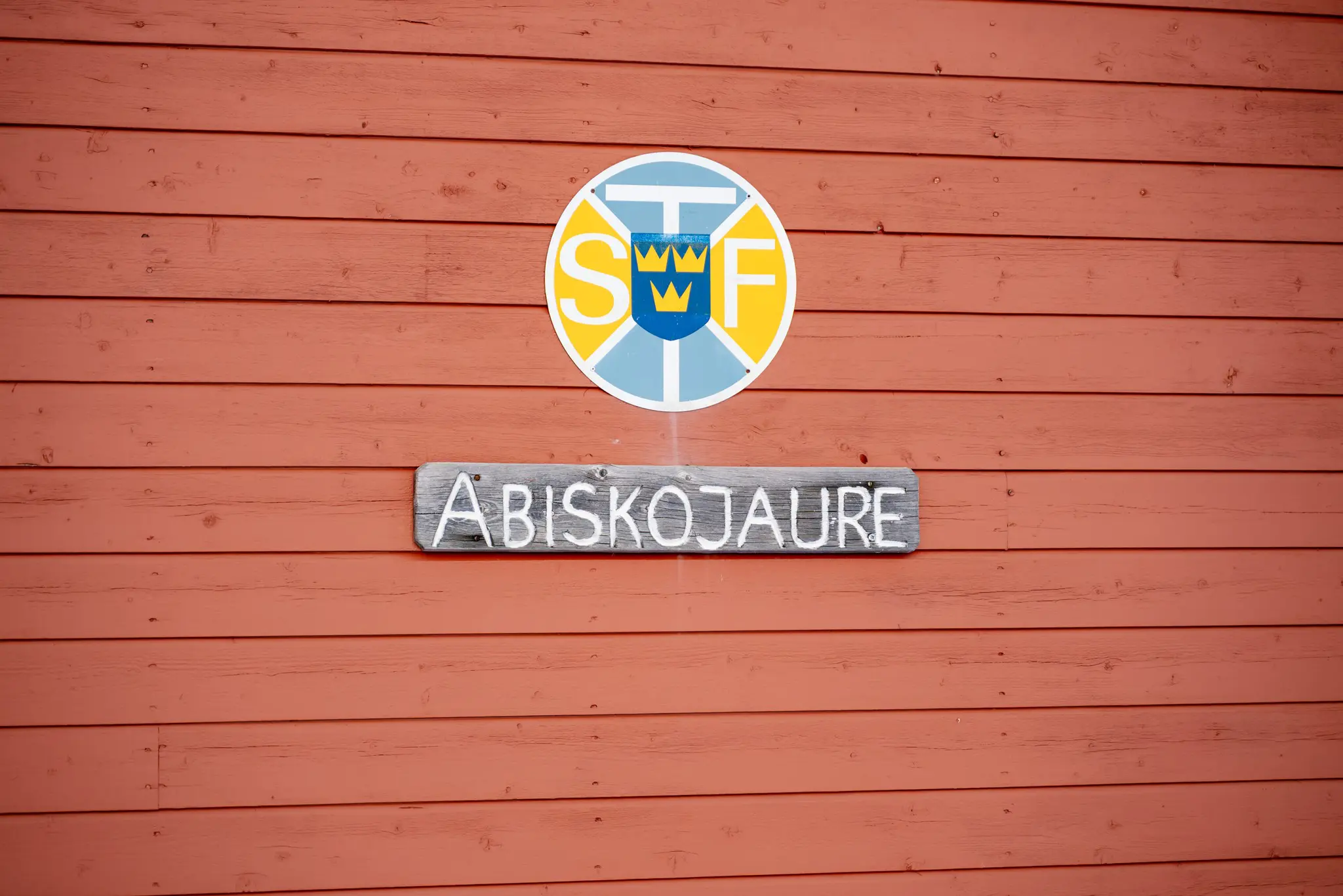 Abiskojaure sign on a red wooden wall in Swedish Lapland