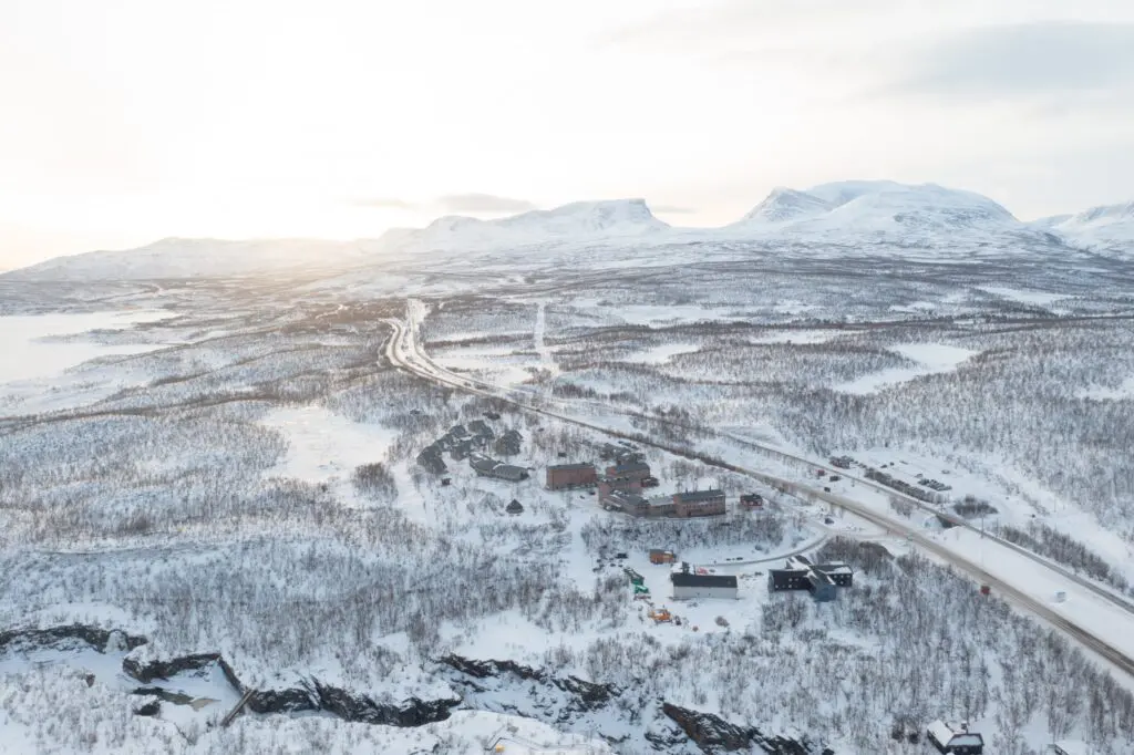 Aerial view of a snowy Arctic landscape with a road and buildings